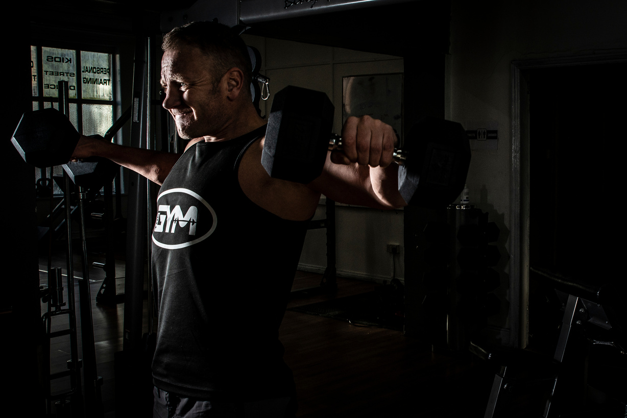 Man Exercising at the Gym With Fixed Weight Dumbbells